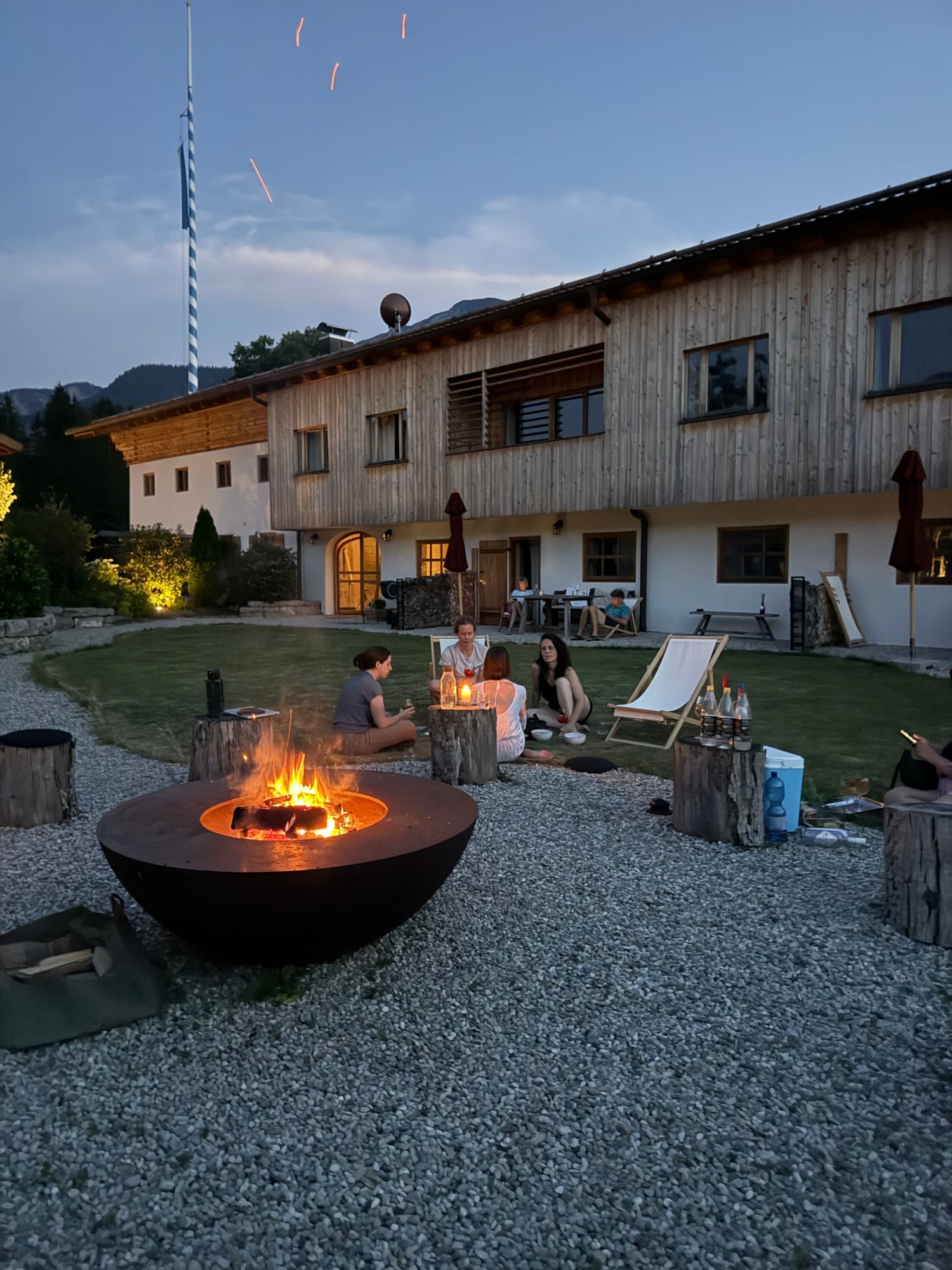 Abendliche Runde an der Feuerschale im Hof eines Holzhauses