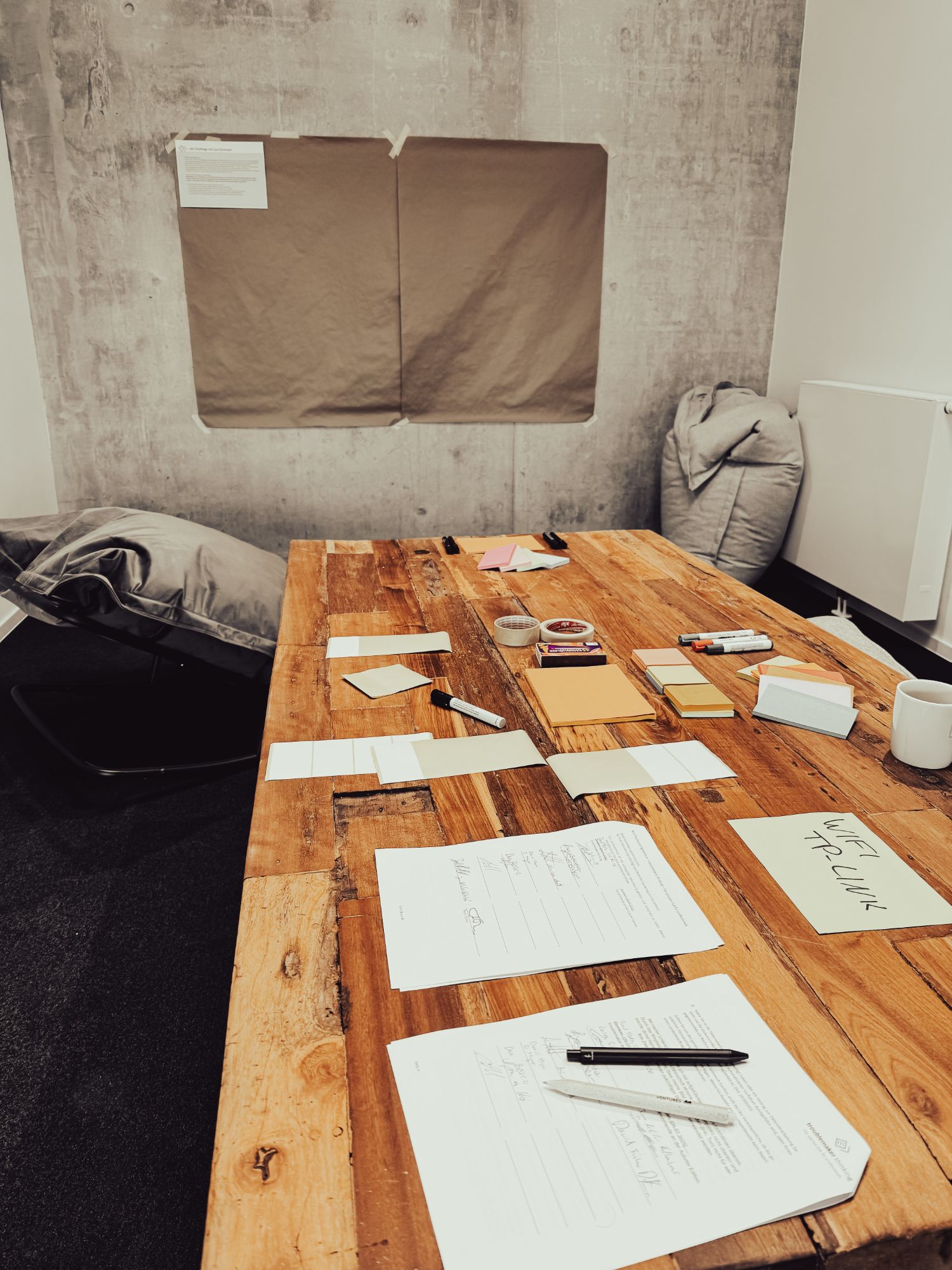 Workshop-Tisch mit Post-its und Markern, Kraftpapier an der Wand