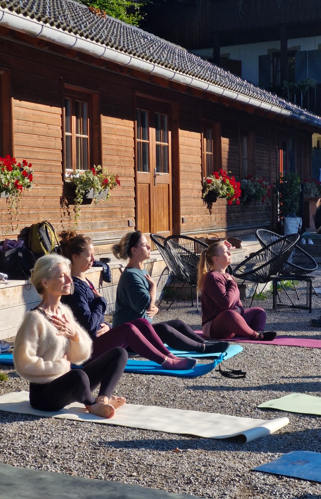 Yoga-Session am Morgen vor einem Holzhaus mit Blumenkästen
